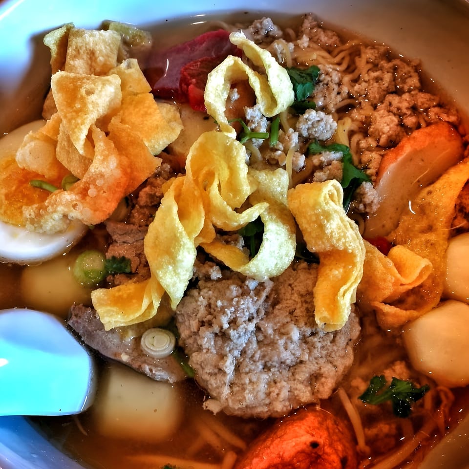 Close-up of Boran Thai Restaurant's noodle soup with crispy wontons, minced pork, and various toppings.
